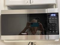 Front view of the Galanz microwave oven showing stainless steel finish and digital control panel with lit display.