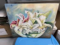 Front view of the oil painting showing white and pink lilies arranged in a bowl with a soft blue-beige background. Signature visible.