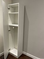 Photo of the wardrobe closet's interior showing shelves and hanging rack inside the single white door.