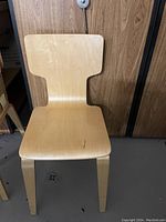 First wooden chair showing curved backrest and seat in light wood tone against wood panel background