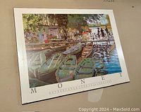 Photo showing plaque-mounted art poster of Monet's Bathers at La Grenouillere, depicting boats and people by the water with vibrant colors.