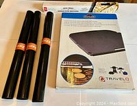 Front view of the Napoleon 2-sided porcelain-enameled cast iron griddle box along with 4 rolled nonstick grill sheets in black packaging.