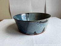 Side view showing the pottery bowl's blue glaze with brown accents and an unglazed base.
