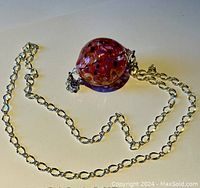 Necklace with large round red and purple glass pendant and silver-tone chain with large links.