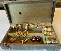 Photo of 10 pairs of costume jewelry earrings organized inside a grey velvet jewelry box with a hinged lid and dividers.