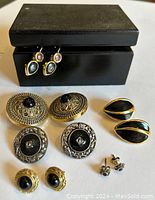 Image showing six pairs of costume jewelry earrings featuring black design elements along with a black wood box.