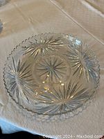 Clear crystal platter on white cloth background showing starburst etched pattern and scalloped edge