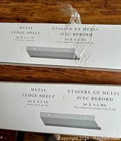 Close-up of packaging showing two boxes labeled 'Metal Ledge Shelf 36 x 3.5 IN Holds up to 40 lbs'