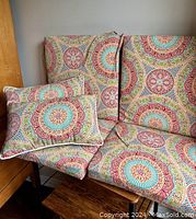 Set of 2 seat cushions and 2 pillows with multicolored mandala pattern fabric displayed on a chair.
