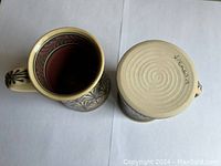 Overhead view showing inside of one mug and base of the other with artist signature 'Teresa W.'