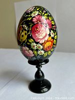Close-up photo of the painted Russian Easter egg on the pedestal showing floral detail.