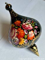 Hand-painted Russian style floral spinning top ornament on a white background.