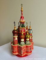 Front view of multi-piece Russian souvenir wooden cathedral model with colorful onion domes and crosses on top.