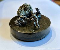 Close-up front view of the pyrite mineral and prospector figurines on metal base