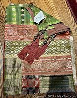 Photo showing multi-coloured patchwork textile folded with tassels visible, highlighting fabric patterns and tassels.
