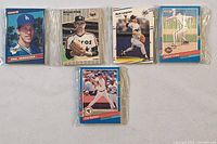 Front view of five sealed baseball card sets showing player images Greg Mershiser, Nolan Ryan, Mark Langston, Floyd Cote, and another player.