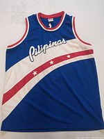 Front view of the blue, red, and white basketball jersey with 'Pilipinas' script and star accents.