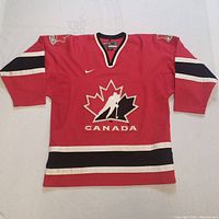 Front view of red Team Canada hockey jersey showing main design, stripes, and logos
