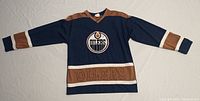 Full view of navy blue and brown Edmonton Oilers jersey showing front logo and color pattern.