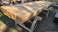 Stack of cedar 2x4 lumber on sawhorses viewed from side