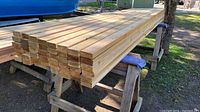 Stack of cedar boards on sawhorses, end view showing board thickness and width