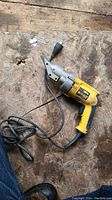 Top view of yellow and black DeWalt DW890 electric metal cutter on wooden surface showing overall tool and attached power cord.