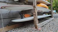 Side view of white paddle board in wooden storage rack