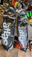 Pair of black Atlas premium snowshoes model 8.30 from top view showing bindings and branding on platform.