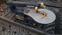 Side view of the full Mastercraft scroll saw on black metal surface showing work area and blade guard