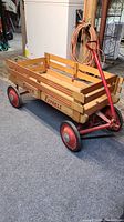Front side view of wooden wagon with red metal handle and wheels showing 'Super Express' text on side panels.