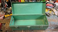Green metal tool box with lid open showing base compartment