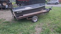 Full view of gray fiberglass boat on single-axle trailer