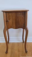 Full front view of the antique Gibbard walnut side table showing curved legs and single door with wooden knob.
