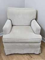 Front view of the creamy beige armchair showing overall upholstery and design.