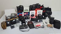 Overview of lot showing cameras, lenses, boxes and accessories on tabletop