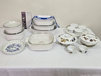 Full lot view showing all items laid out on white cloth, including Corningware baking dishes and covered Evesham servers and ramekins.