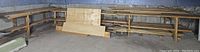 Long view of wood lot showing plywood boards leaning against wall and wooden planks on shelves.
