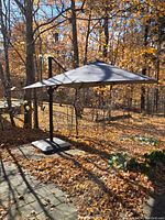 umbrella fully open in wooded backyard on base
