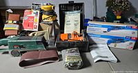 Full view of lot including Mastercraft multi-crafter kit box, sandpaper sheets, sanding belts, and additional tools with manuals.
