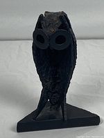 Front view showing full owl sculpture with circular eyes and textured body.