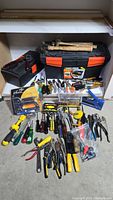 Full overview of lot contents including tool boxes, hammers, screwdrivers, pliers, and other hand tools laid out on floor