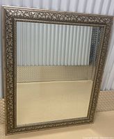 Front view of the rectangular wall mirror showing the leaf motif decorative frame and reflective glass surface.