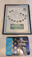 Framed lithograph showing multiple Canadian coins and a 1967 one-dollar bill under glass in black frame