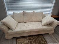 Front view of sofa showing seat cushion and four back cushions beneath window blinds