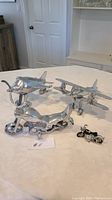 Wide shot of two metal airplane models, one large metal motorcycle, and one small motorcycle clock on a white surface.