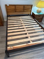 Full view of the queen size bed frame with wooden slats and solid oak headboard attached, showing condition and materials.