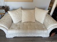 Front view of loveseat showing three back cushions, rolled arms and skirt base