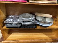 Bakeware collection including baking pans stacked on wooden shelf