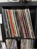 Photo of a shelf with approximately 63 vinyl LP records showing spines of various albums