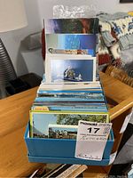 Photo of the blue storage box holding assorted postcards tightly packed inside in vertical orientation.